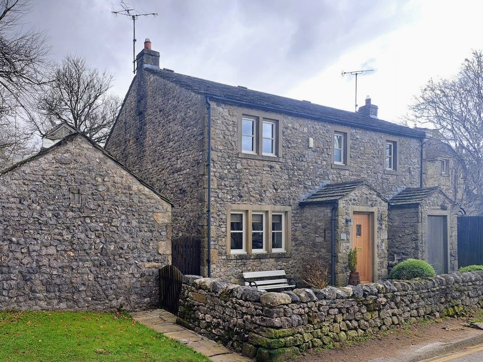 A stone house with a door and windows at Woodside Cottage in Malham