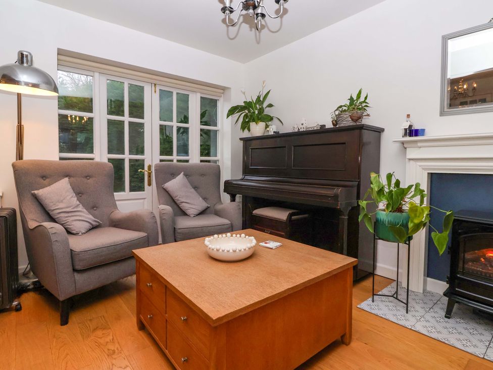 A living room with a piano and two chairs at Lair Close House in Harrogate
