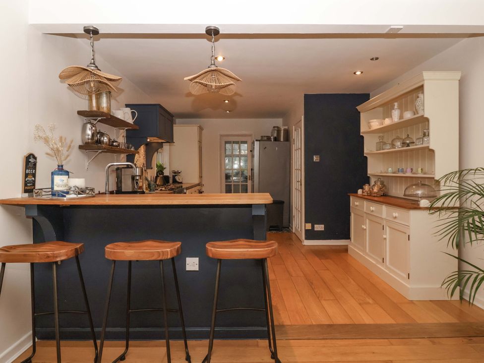 A kitchen with bar stools and shelves at Lair Close House in Harrogate