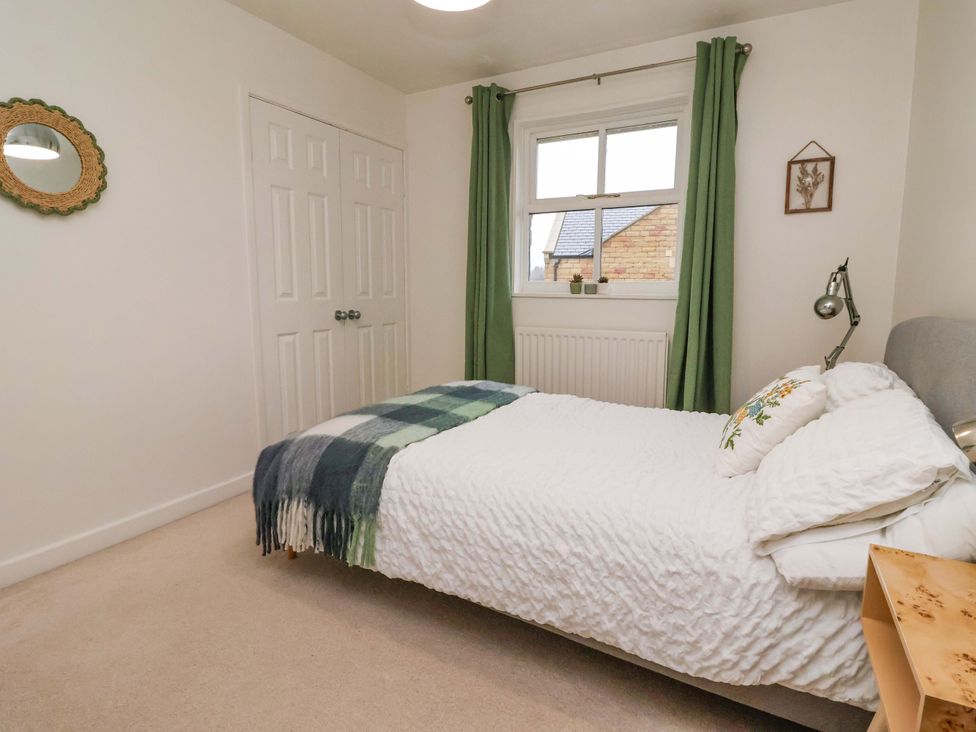 A bedroom with a bed and green curtains at Lair Close House in Harrogate