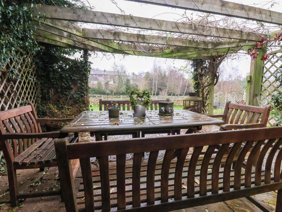 A garden with wooden table and chairs under a pergola at Lair Close House Harrogate