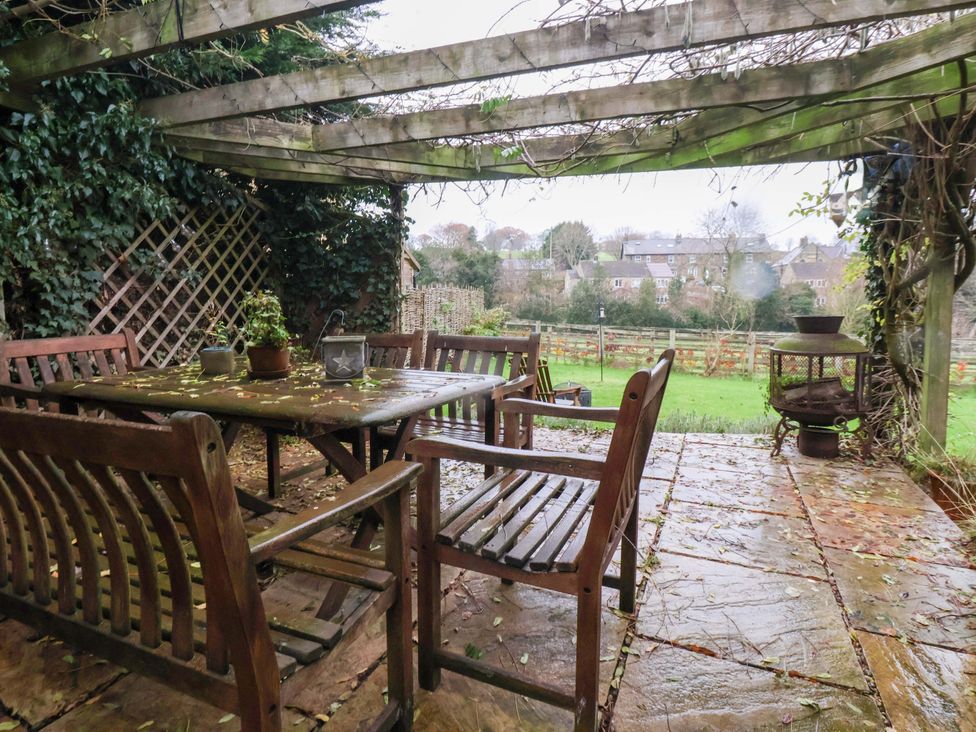 A garden scene with a table and chairs under a pergola at Lair Close House in Harrogate