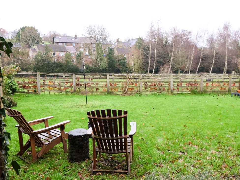 A garden with two wooden chairs and a fence at Lair Close House in Harrogate