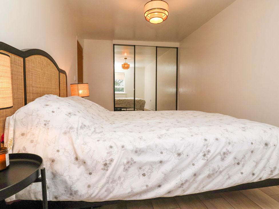 A bedroom with a bed and mirrors at Apartment in Harrogate