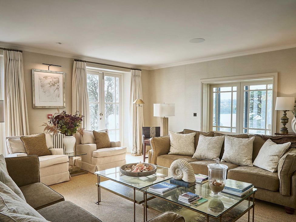 A living room with sofas and a glass table at Craig y Don in Glyngarth near Llandegfan