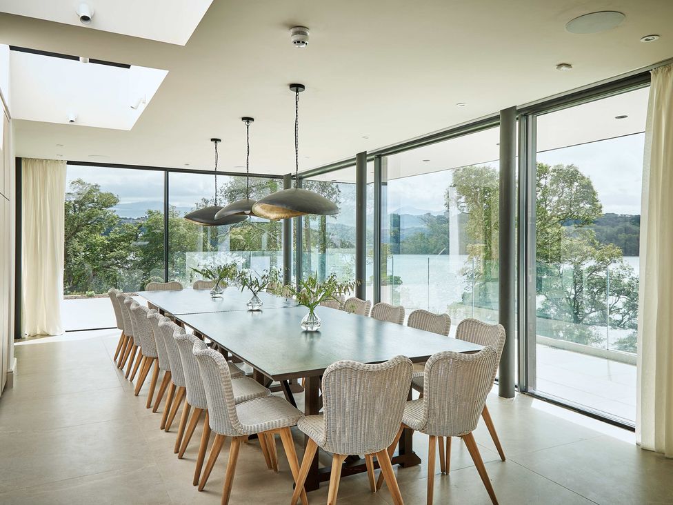 A dining room with a long table and chairs at Craig y Don in Glyngarth near Llandegfan