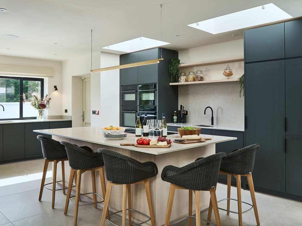 A kitchen with an island and bar stools at Craig y Don Glyngarth near Llandegfan