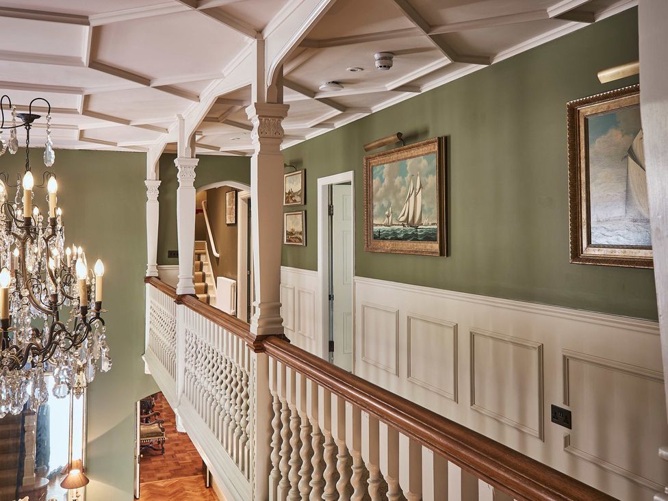 A hallway with a chandelier and paintings at Craig y Don in Glyngarth near Llandegfan