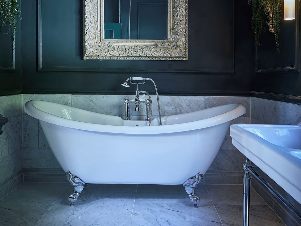 A bathroom with a white bathtub and a sink at Craig y Don Glyngarth near Llandegfan