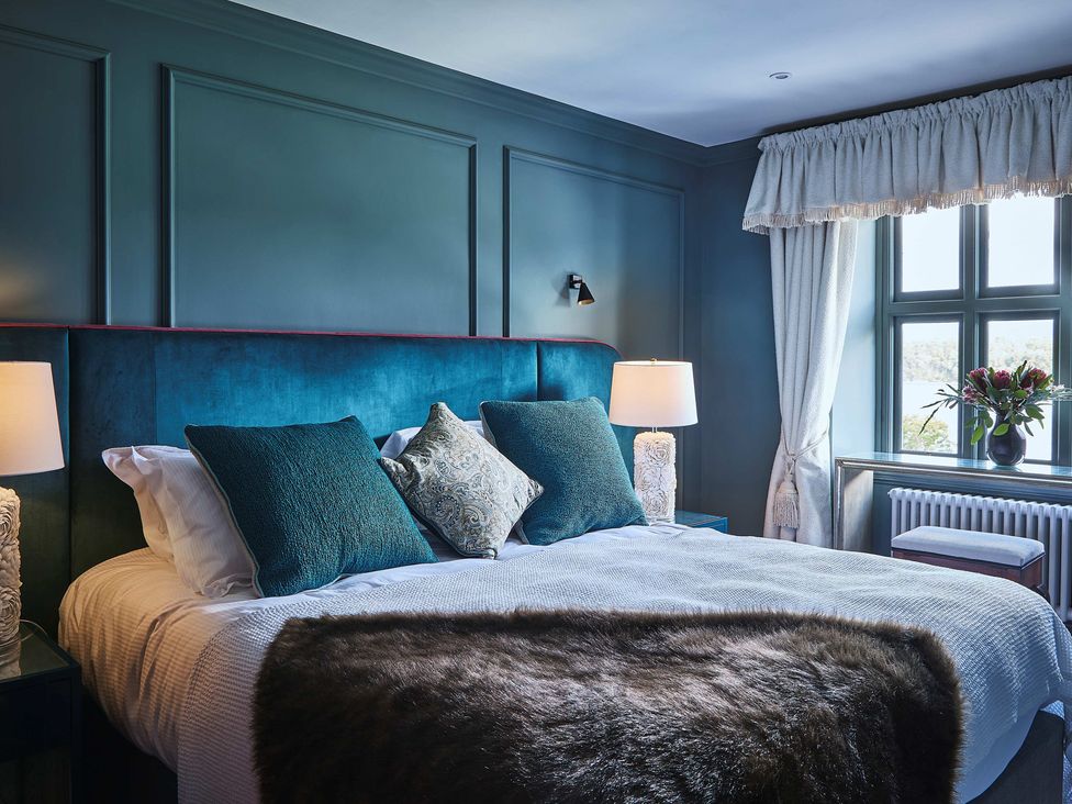 A bedroom with a bed and curtains at Craig y Don in Glyngarth near Llandegfan