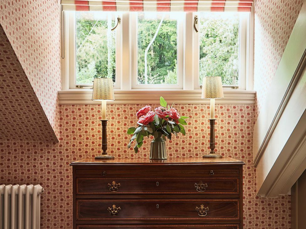 A hallway with a chest of drawers and flowers at Craig y Don in Glyngarth near Llandegfan