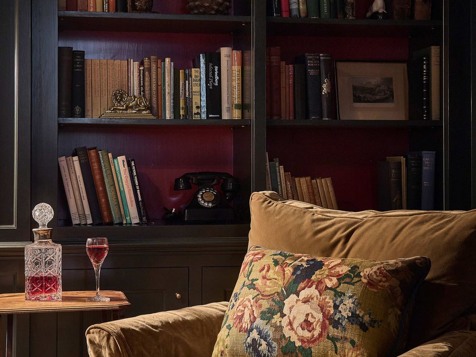 A living room with bookshelves and an armchair at Craig y Don Glyngarth near Llandegfan