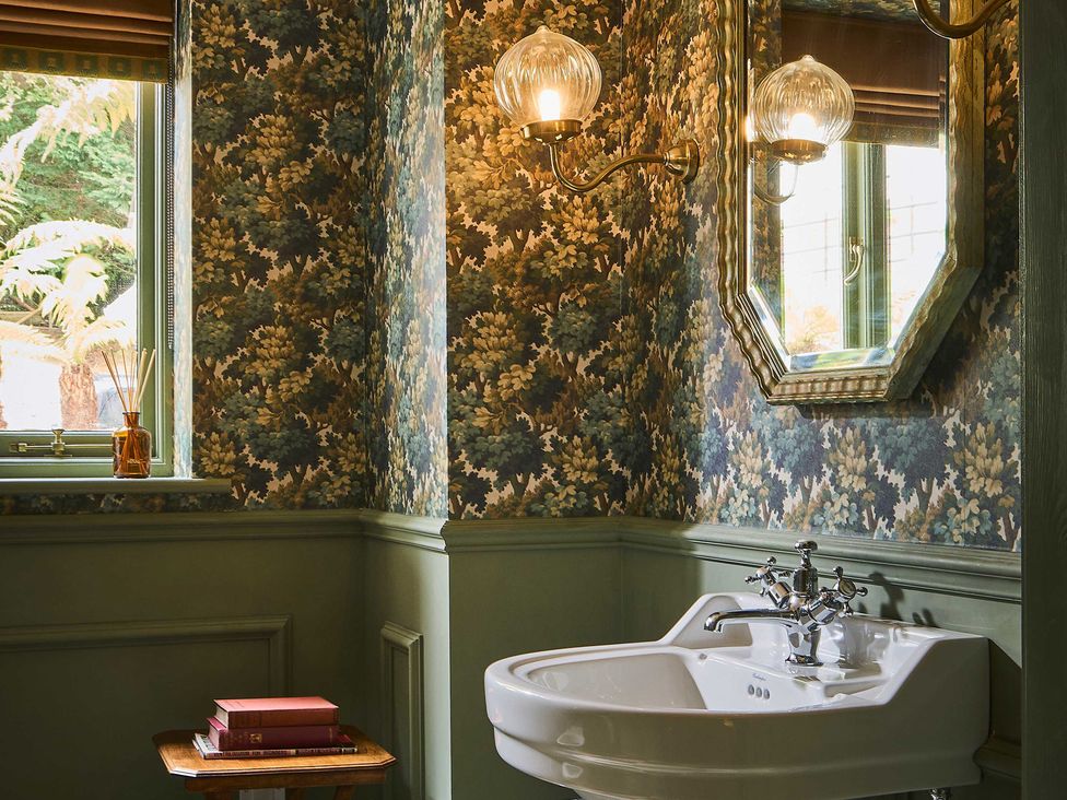 A bathroom featuring a sink, mirror, and decorative items at Craig y Don Glyngarth near Llandegfan