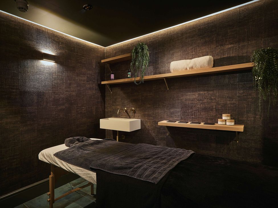 A spa room with a massage table and washbasin at Craig y Don Glyngarth near Llandegfan