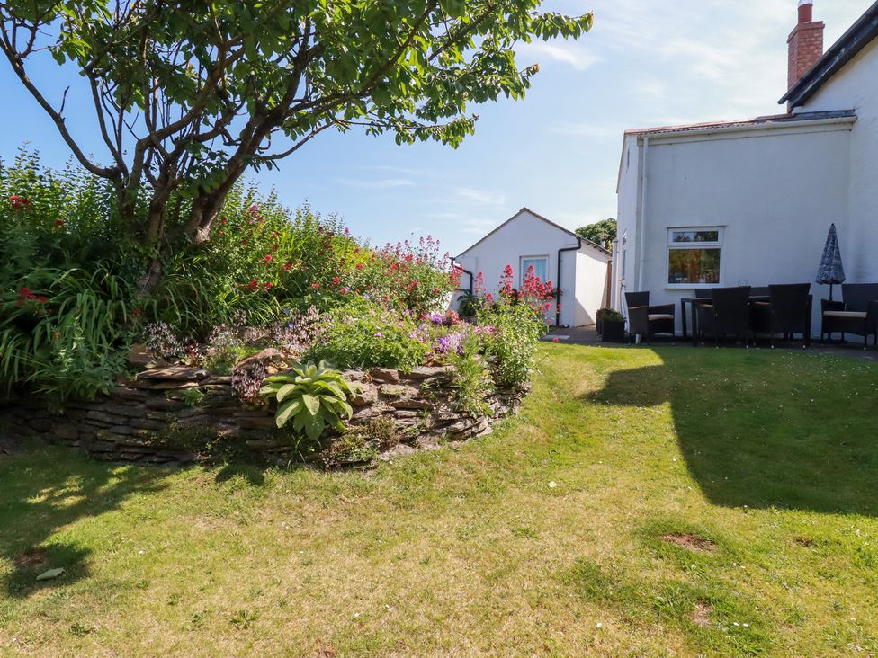 A garden with flowers and seating area at Bramble Cottage in Gwithian near Connor Downs