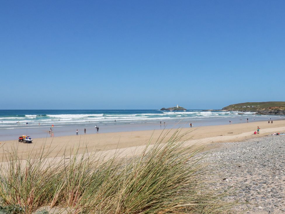A beach with people enjoying the sun and waves at Bramble Cottage in Gwithian near Connor Downs