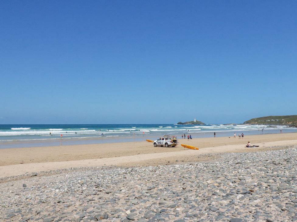 A beach scene with people and a lifeguard vehicle at Bramble Cottage in Gwithian near Connor Downs