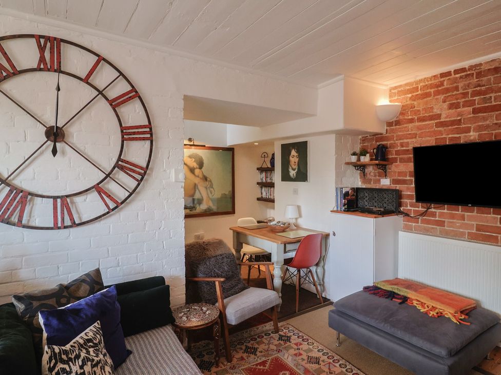 A living room with a clock on the wall and a sofa at The Clock Tower in Rousdon, Nr Lyme Regis