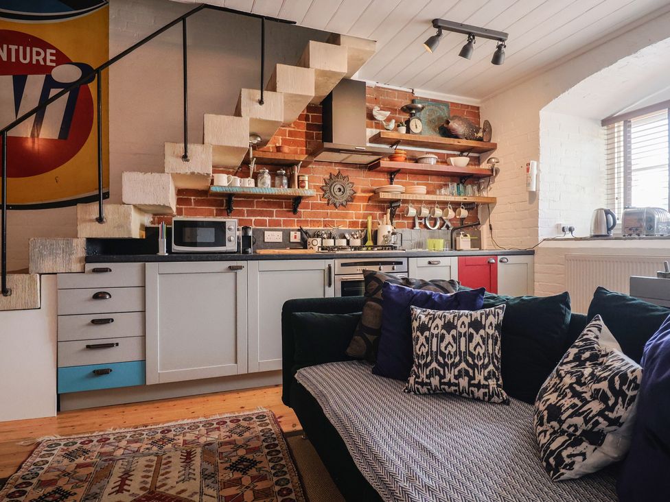 A kitchen with a staircase, cabinets, microwave, and couch at The Clock Tower in Rousdon, Nr Lyme Regis