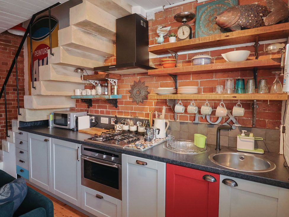 A kitchen with a sink, stove, and shelves at The Clock Tower in Rousdon, Nr Lyme Regis