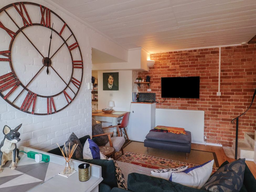 A living room with a clock and sofa at The Clock Tower in Rousdon, Nr Lyme Regis