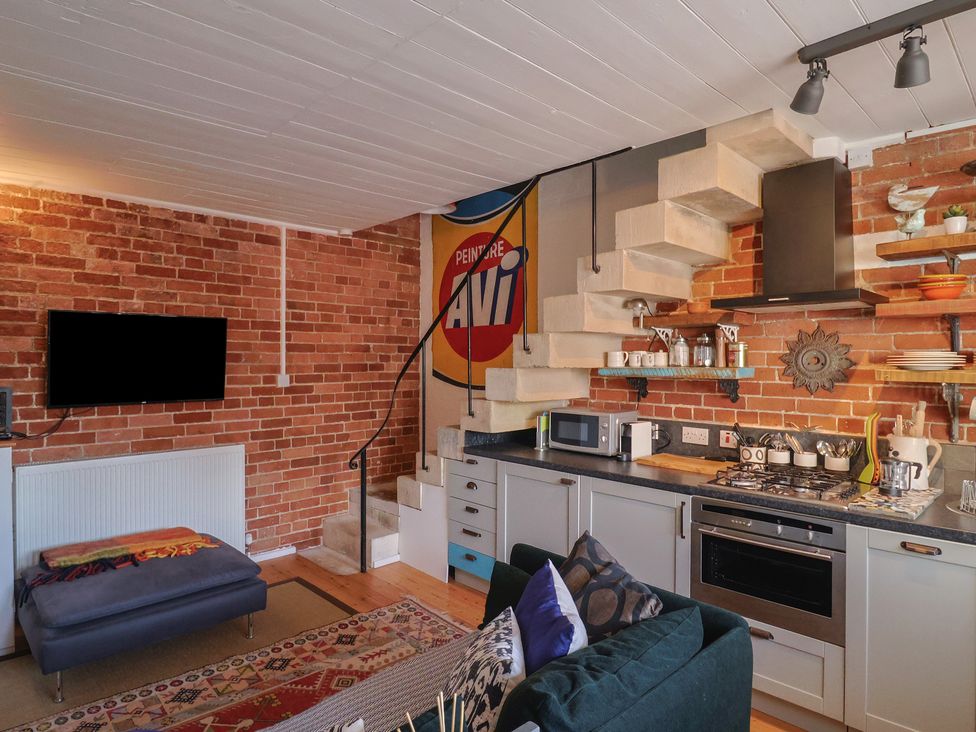A living room with a kitchen area and stairs at The Clock Tower in Rousdon, Nr Lyme Regis