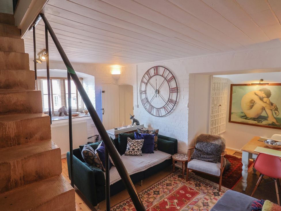 A living room with a sofa, clock, and artwork at The Clock Tower, Rousdon, Nr Lyme Regis