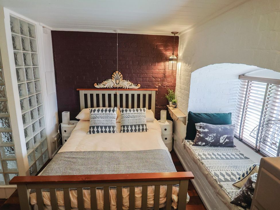 A bedroom with a bed and window seating at The Clock Tower in Rousdon, Nr Lyme Regis