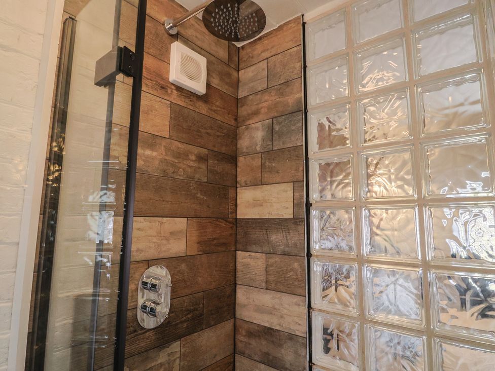 A shower with wooden tiles and glass block wall at The Clock Tower in Rousdon, Nr Lyme Regis