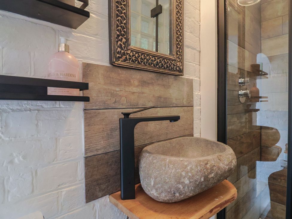 A bathroom with a stone sink and mirror at The Clock Tower, Rousdon, Nr Lyme Regis