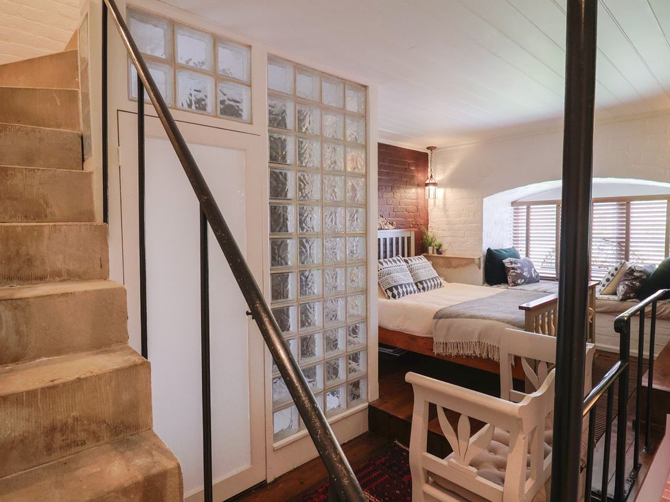 A bedroom with a bed and glass block wall at The Clock Tower Rousdon, Nr Lyme Regis
