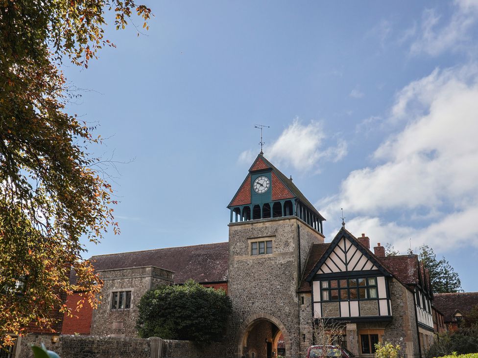 A clock tower with a building and trees at The Clock Tower Rousdon, Nr Lyme Regis