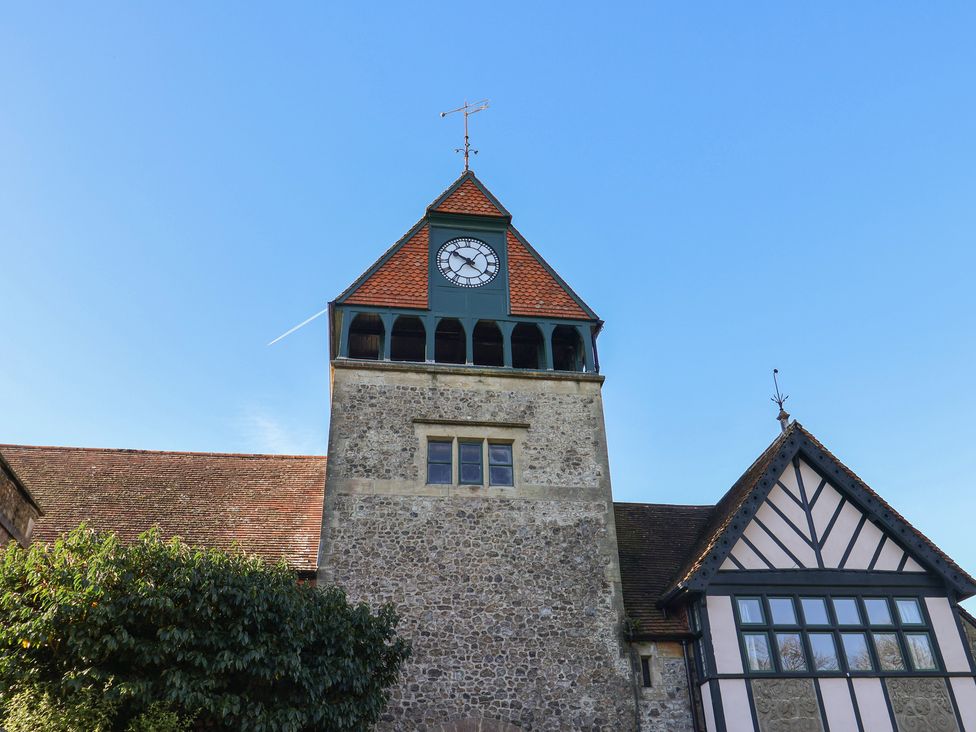 A clock tower with a visible clock and windows at The Clock Tower in Rousdon, Nr Lyme Regis