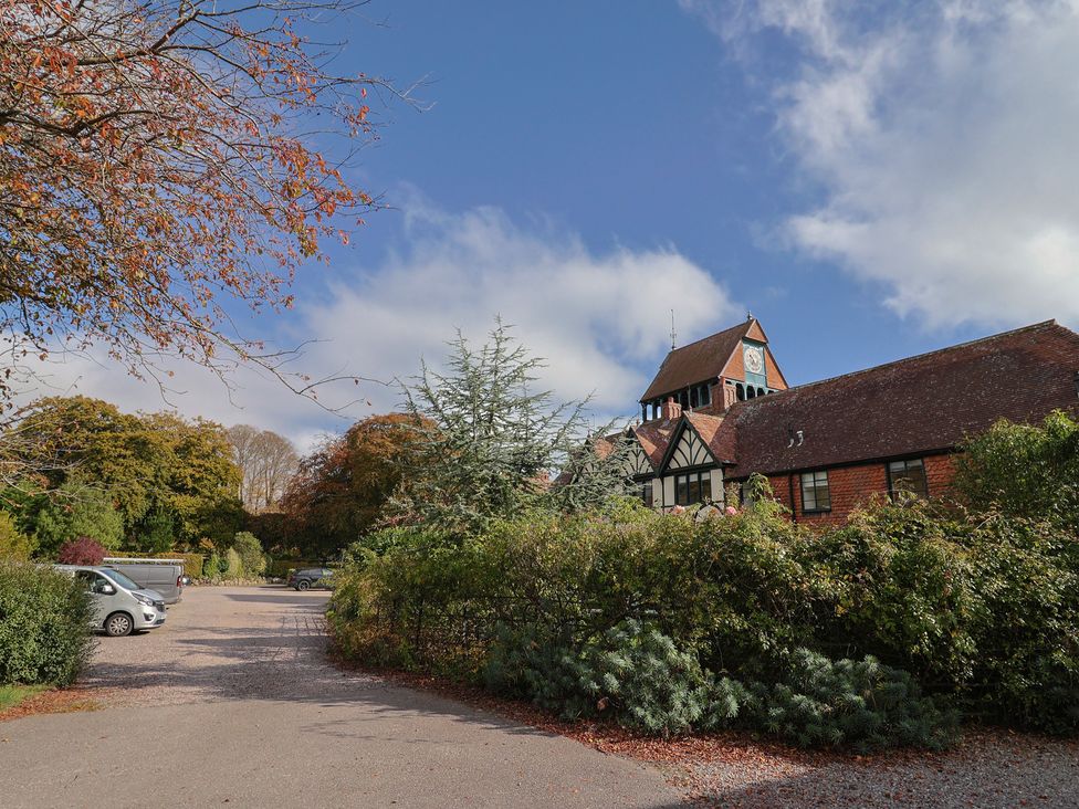 An outdoor view of a building and parking area at The Clock Tower in Rousdon, Nr Lyme Regis