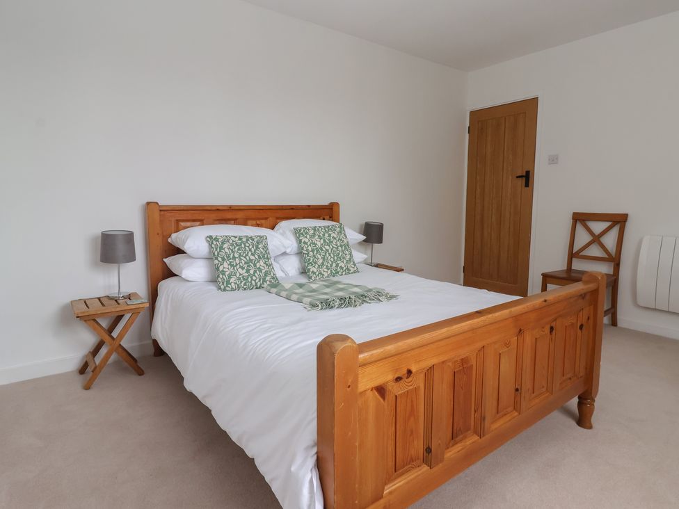 A bedroom with a bed, bedside lamp, and chair at Pear Tree Cottage in Great Ouseburn