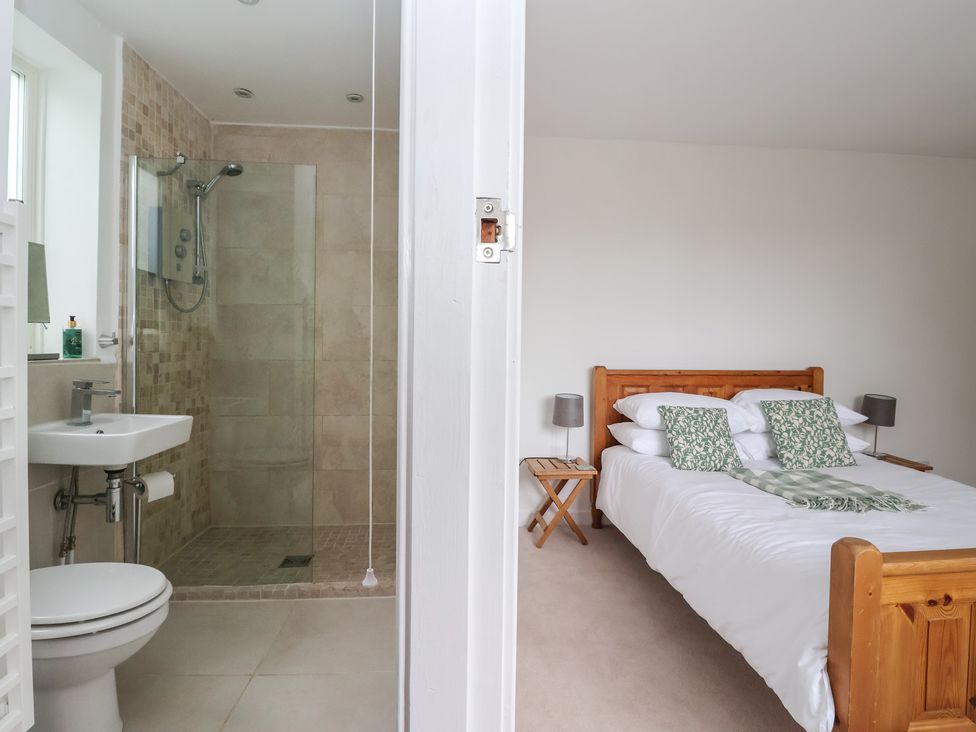 A bathroom with shower and a bedroom with bed at Pear Tree Cottage in Great Ouseburn
