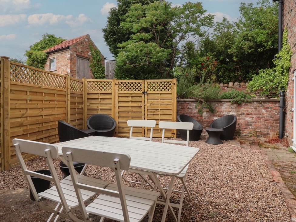 A garden with a table and chairs surrounded by a fence at Pear Tree Cottage in Great Ouseburn