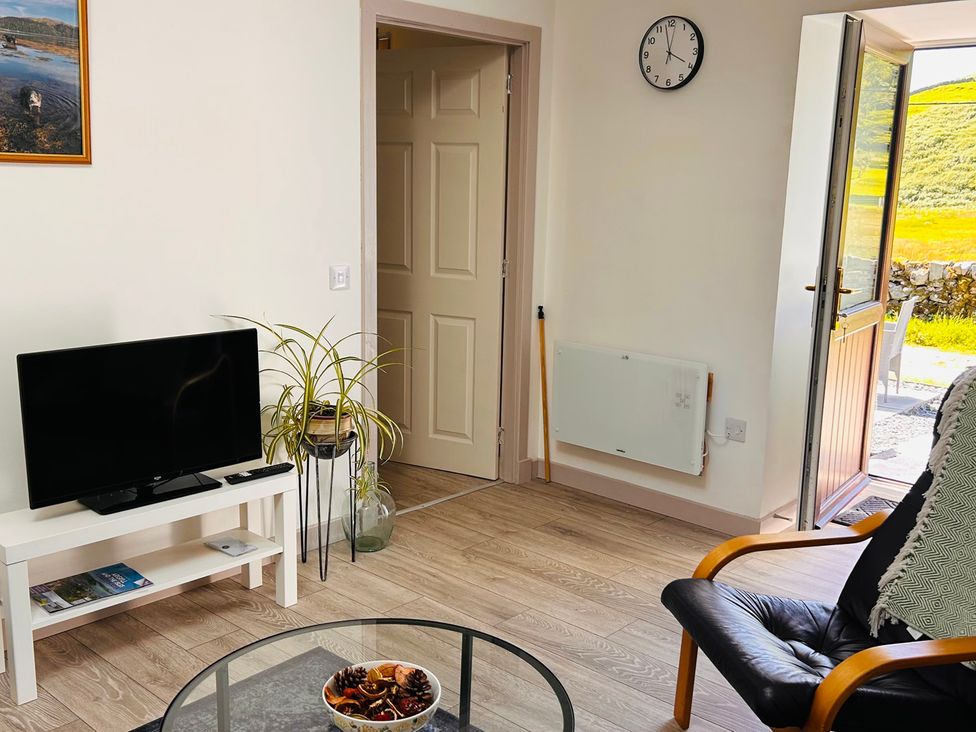 A living room with a TV and a door at Bathach Mor in Balvicar, Isle Of Seil