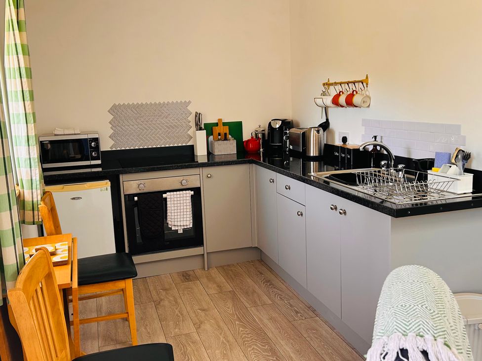A kitchen with appliances and dining area at Bathach Mor Balvicar, Isle Of Seil