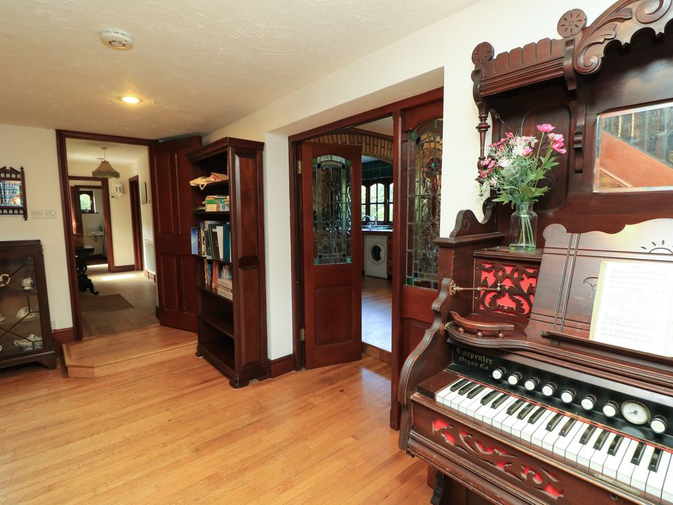 A hallway with a piano and bookshelf at The Chapel in Northwood, Isle Of Wight
