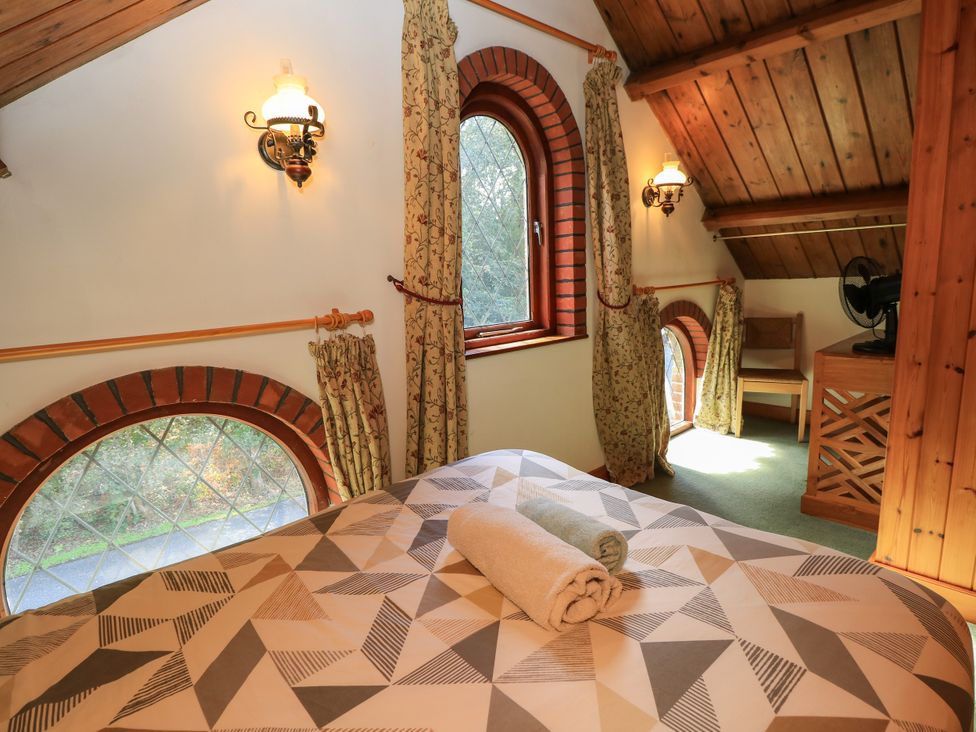 A bedroom with a bed, windows, curtains, and a fan at The Chapel in Northwood, Isle Of Wight