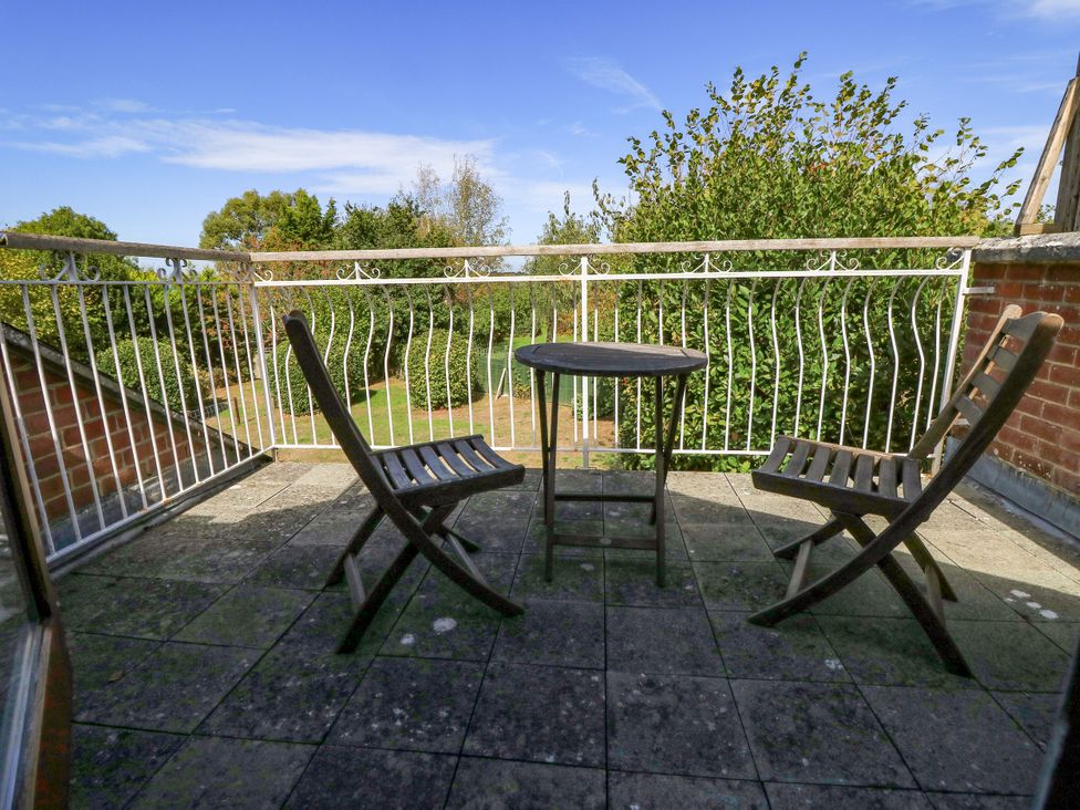 A balcony with two chairs and a table overlooking a garden at The Chapel in Northwood, Isle Of Wight