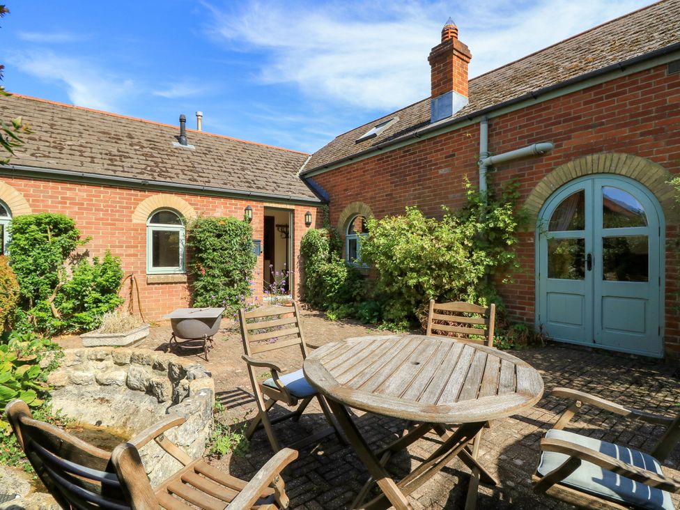 A garden with a table and chairs in front of a brick building at The Chapel in Northwood, Isle Of Wight