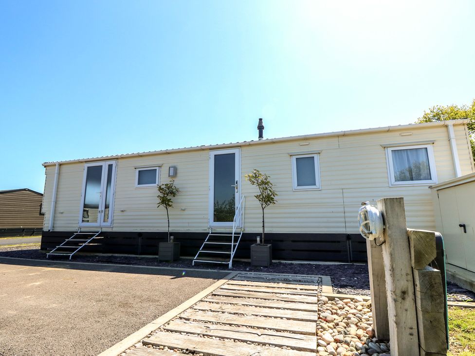 A static caravan with steps and trees at MillRythe Holiday Park (Dunlin Walk 13) Hayling Island