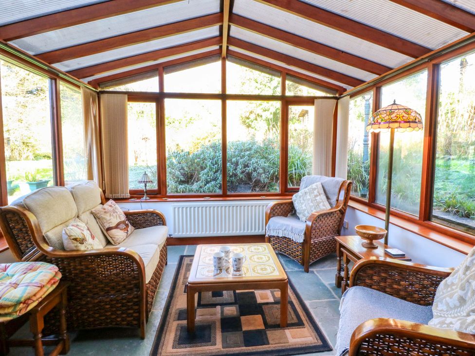 A conservatory with seating and windows at Maggie's Barn in Brecon