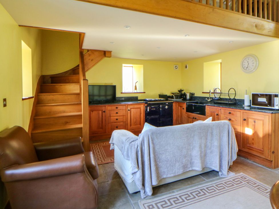 A kitchen with a staircase and television at Maggie's Barn in Brecon