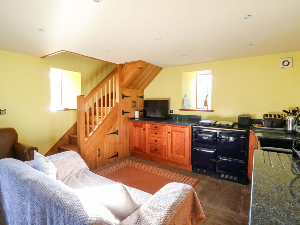 A kitchen with a sofa and staircase at Maggie's Barn Brecon