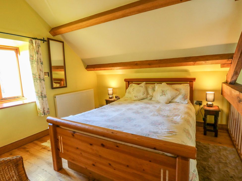 A bedroom with a bed and bedside table at Maggie's Barn in Brecon