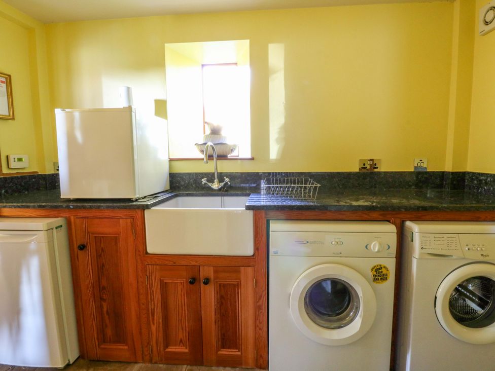 A laundry room with a fridge, sink, and washing machine at Maggie's Barn in Brecon
