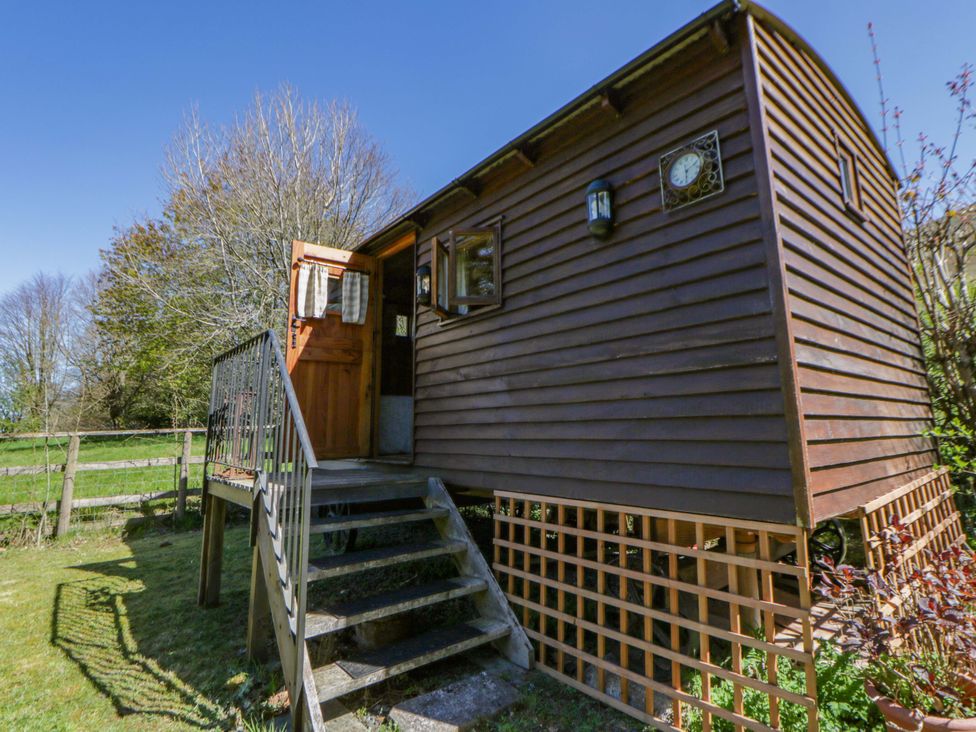 A shepherd's hut with steps and wooden features at Bill’s Shepherds Hut near Talgarth